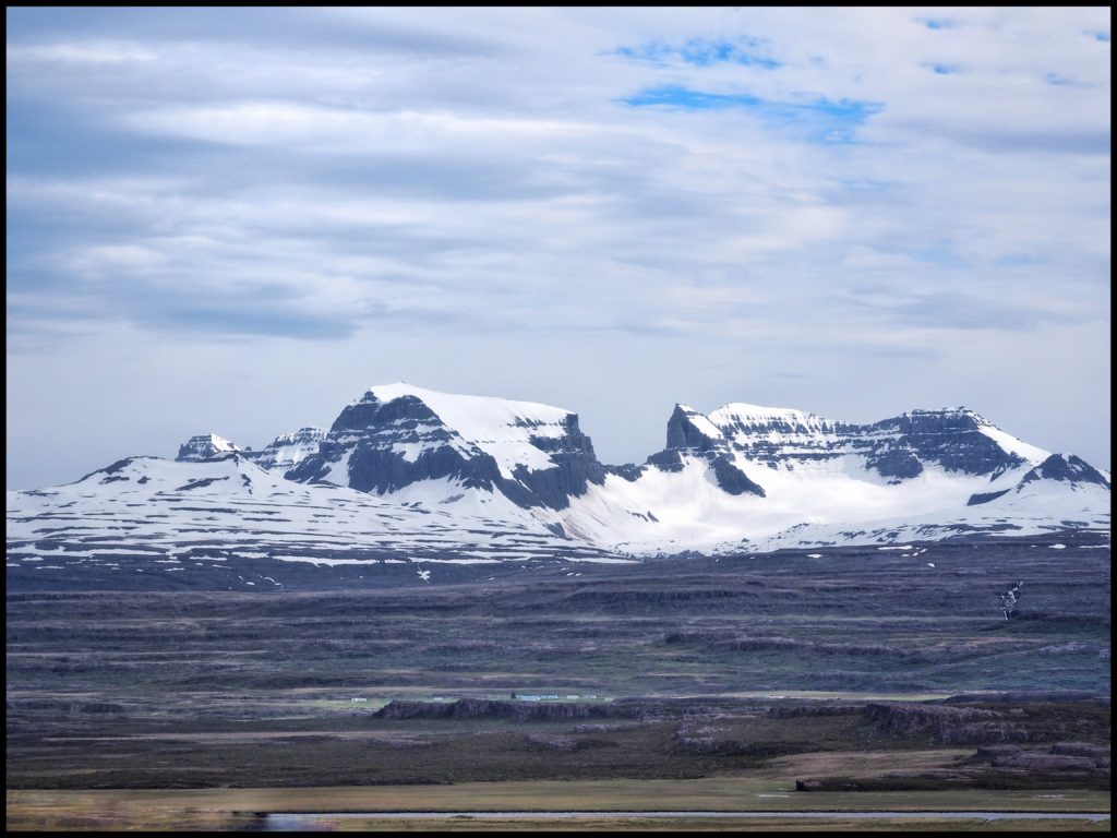 A farm set on a bluff at the foot of snowy mountains