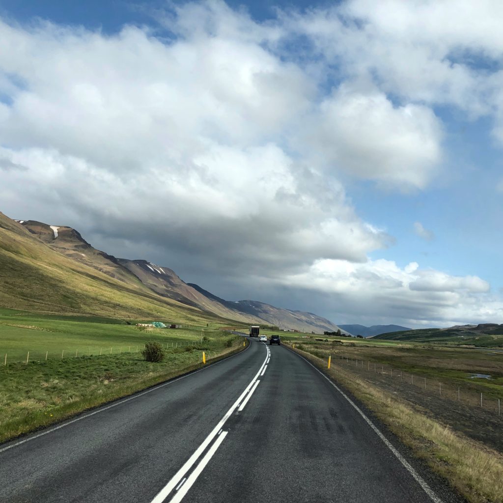 Road way with blue skies, golden mountain tops and green fields